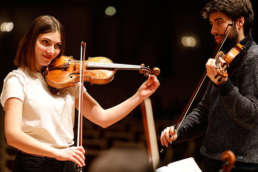 Studentin und Student mit Geigen während einer Probe