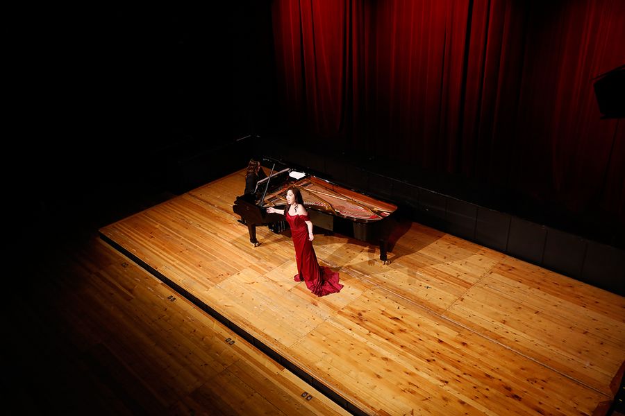 Sängerin in rotem Kleid und Pianistin am Flügel auf der Bühne des Studiosaals