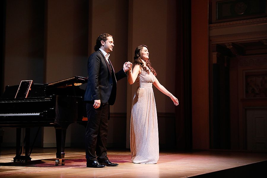 Studentin und Pianist stehen vor einem Flügel auf einer Bühne bereit für den Schlussapplaus
