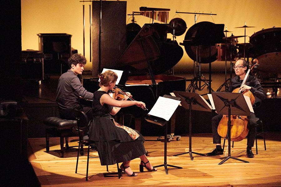 Trio aus Studierenden mit Cello, Geige und Klavier auf einer Bühne