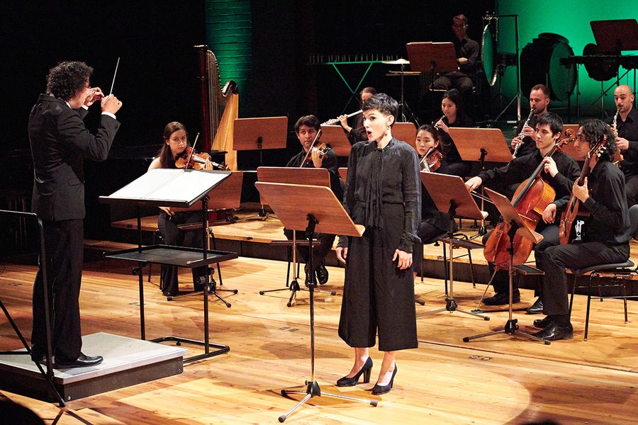 Professor Manuel Nawri dirigiert ein Ensemble und eine singende Studentin