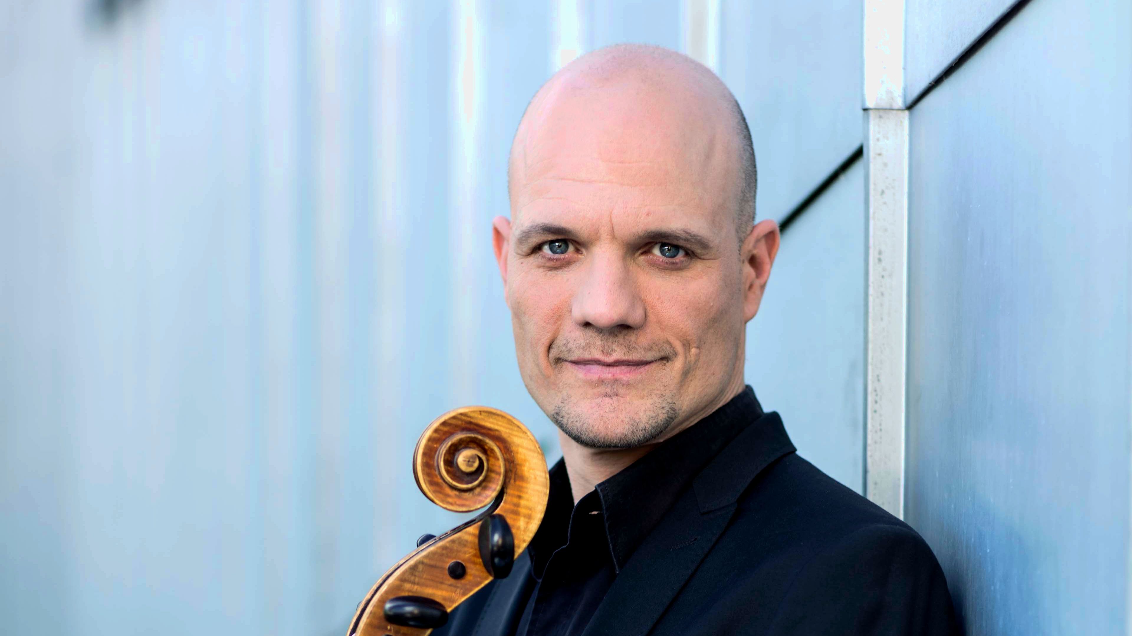 Mann mit Cello vor hellblauem Hintergrund