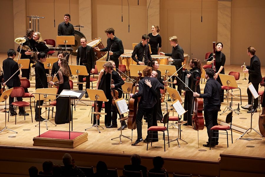 Mitwirkende des Ensemble Eisler Sinfonietta umarmen sich auf der Bühne im Großen Saal des Konzerthaus Berlin