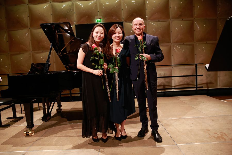 Drei Flötisten mit Rosen und Querflöten auf einer Bühne