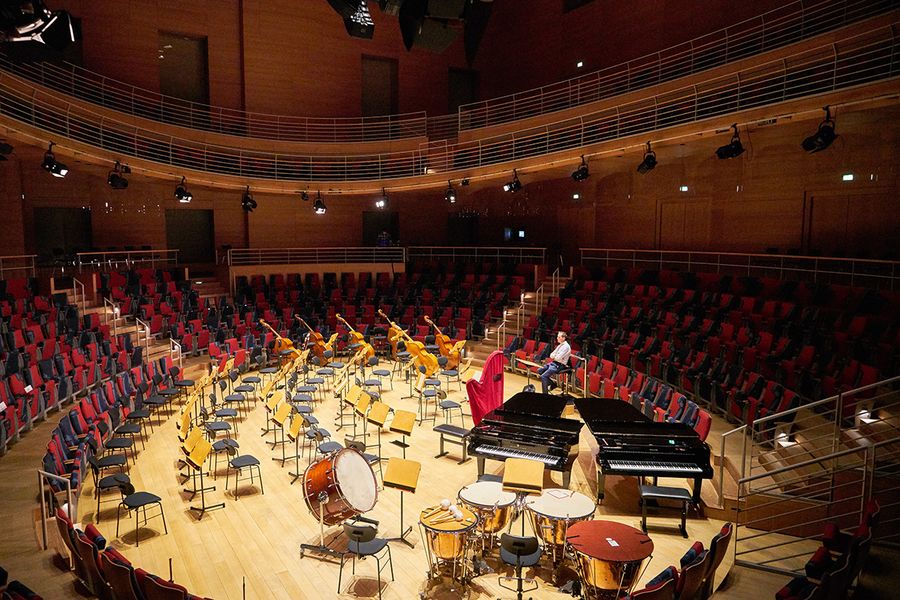 Runder Konzertsaal mit runder Bühne in der Mitte mit Stühlen, Notenständern, Schlagwerken und Flügel