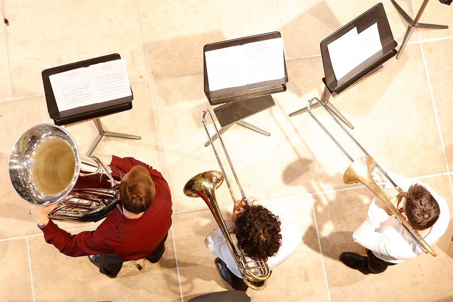 Blick von oben auf zwei Posaune spielende Studenten und einen Tuba spielenden Studenten