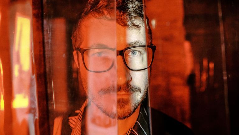 Mann mit Brille und Bart im Porträt mit rotem Licht