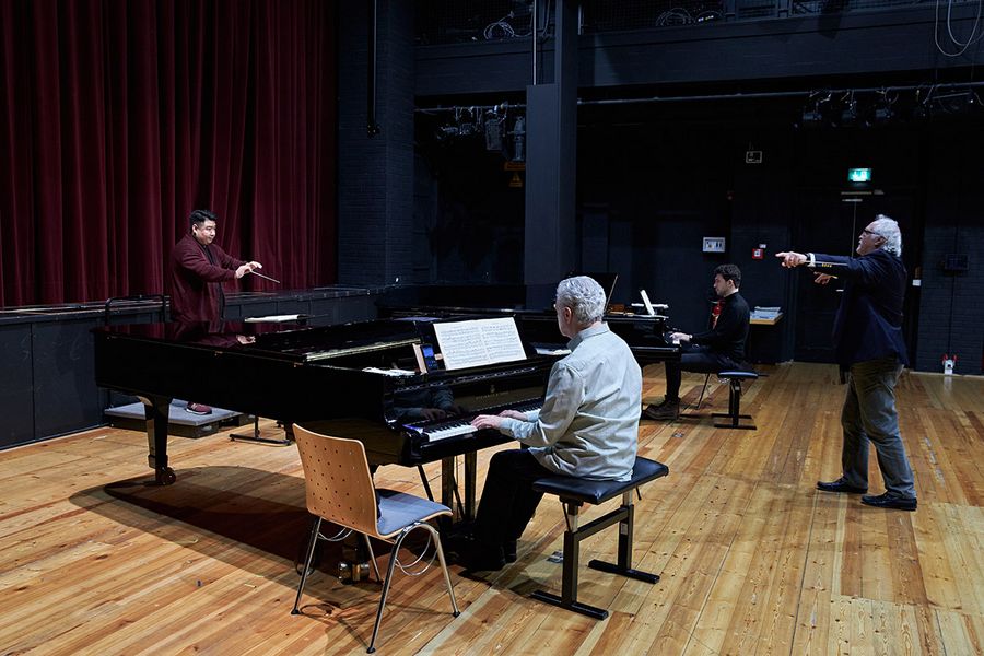 Dirigierstudent in Interaktion mit Sir Donald Runnicles und zwei Pianisten während eines Meisterkurses
