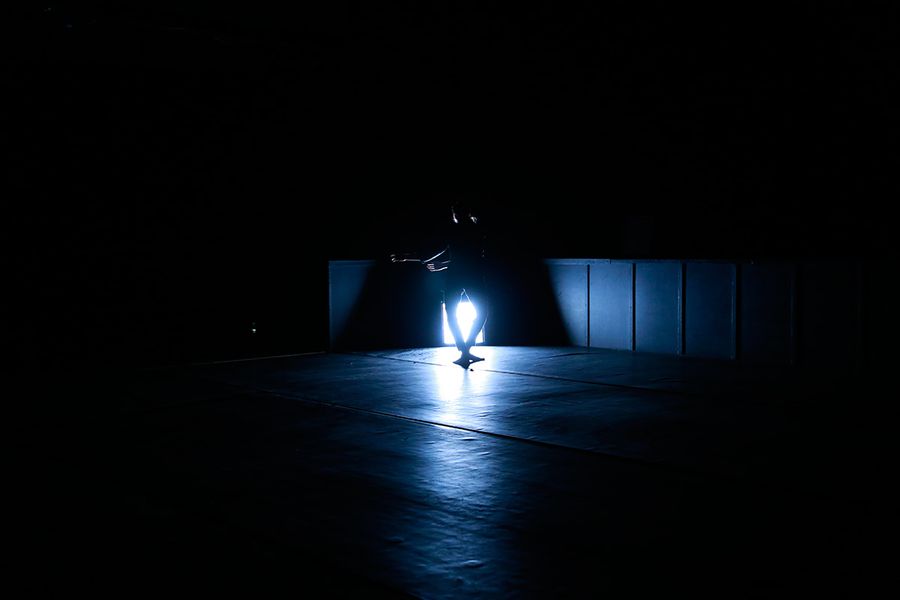Silhouette eines tanzenden Menschen auf einer dunklen Bühne