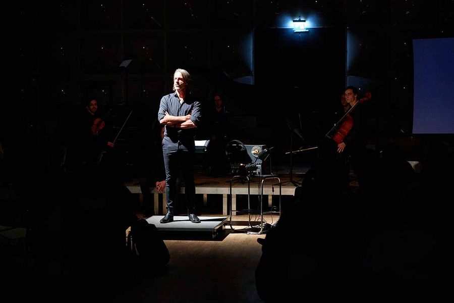 Richard David Precht steht mit verschränkten Armen vor einem Ensemble aus Studierenden