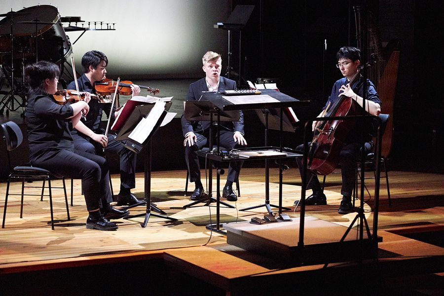 Ensemble aus Geige, Bratsche, Sänger und Cello auf einer Bühne während eines Konzertes