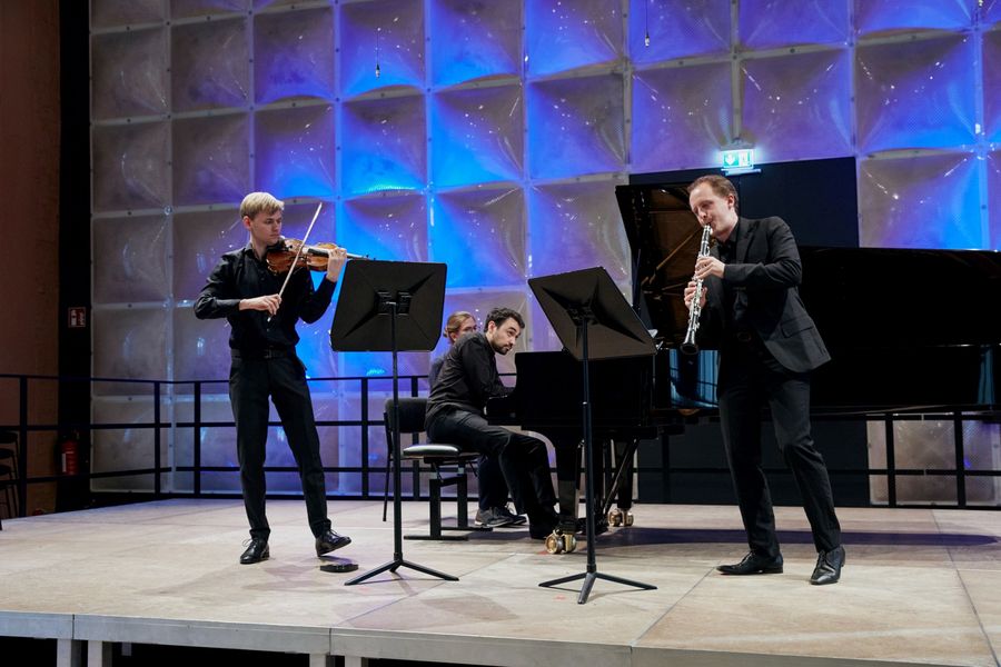 Trio bestehend aus Violine, Klarinette und Klavier musiziert auf der Bühne