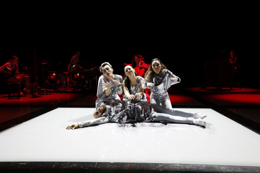 Drei Sängerinnen sitzen vor am Boden ausgestreckt liegendem Sänger