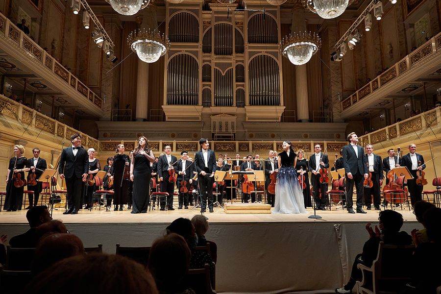 Orchester und Sänger*innen stehen zum Applaus auf der Bühne des Berliner Konzerthauses