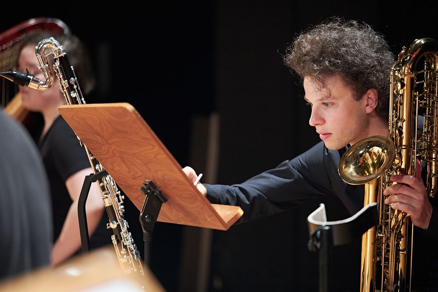 Student mit Saxophon notiert etwas in seiner Partitur