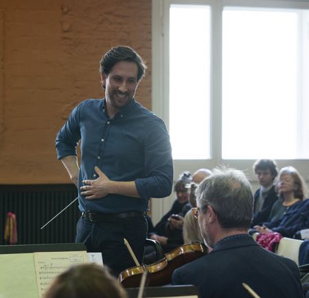 Dirigent spricht lächelnd mit Konzertmeister auf der Bühne