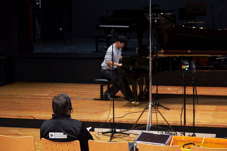 Pianist spielt, im Vordergrund ein Tontechniker 