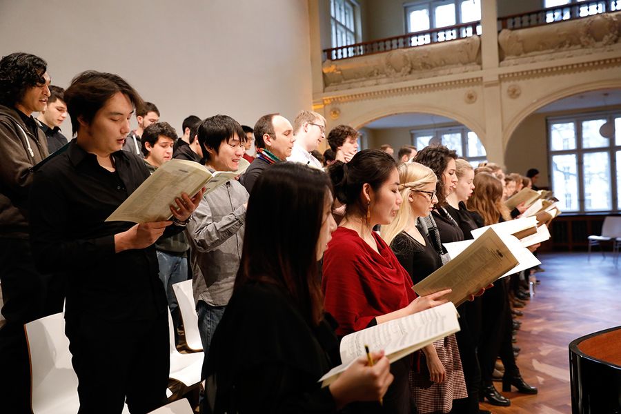 Studierende im Chor mit Noten in den Händen während einer Probe