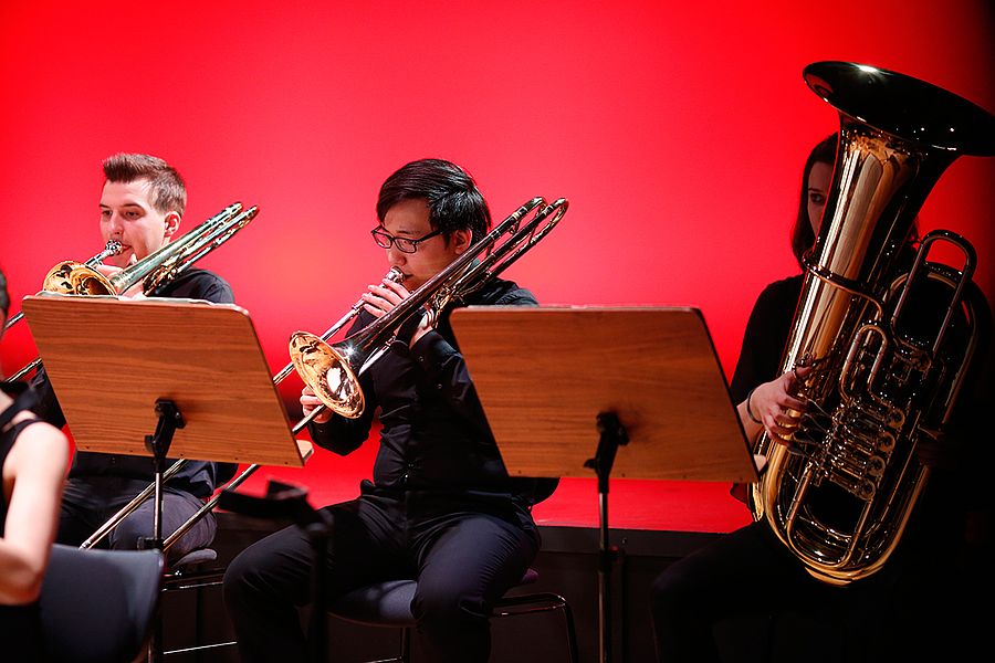 Zwei Studenten mit Posaunen und Studentin mit Tuba während einem Konzert