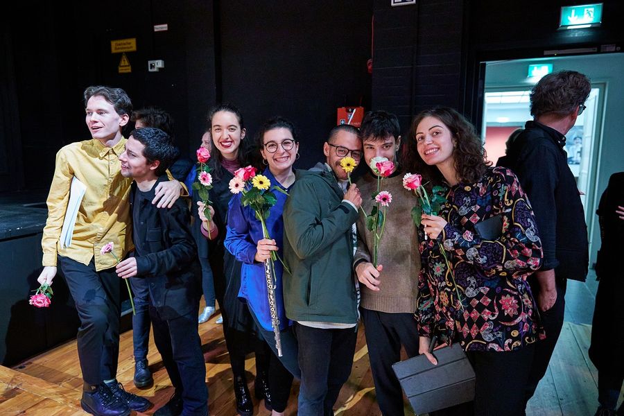 Eine kleine Gruppe von Mitwirkenden hält Blumen in der Hand und lächelt in die Kamera
