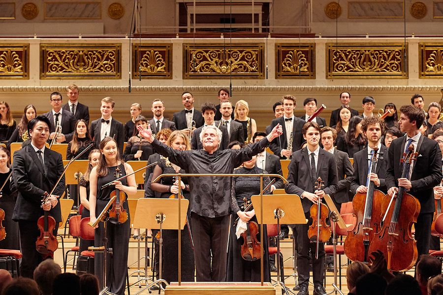 Dirigent und Studierende im Orchester stehen auf der Bühne des Berliner Konzerthauses während des Applauses