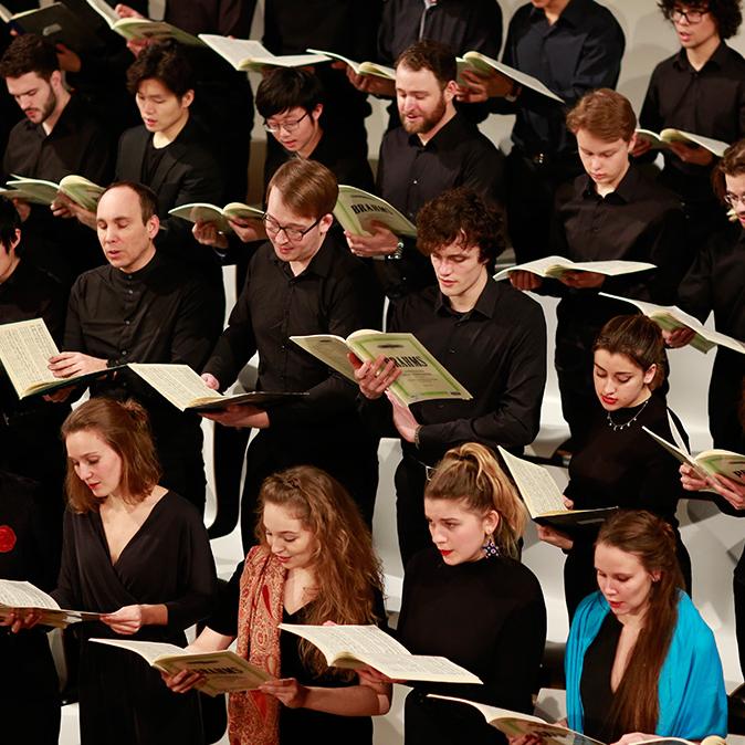 Singende Studierende im Chor mit Noten während eines Konzertes