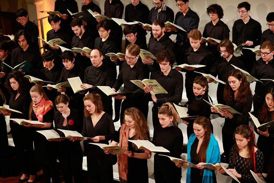 Singende Studierende im Chor mit Noten während eines Konzertes