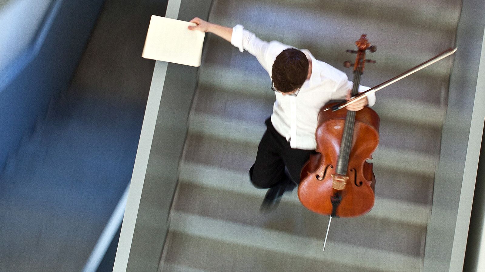 Junger Mann mit Cello auf Treppe