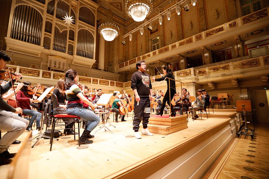 Singender Student und Studierende im Orchester während einer Probe auf der Bühne des Berliner Konzerthauses
