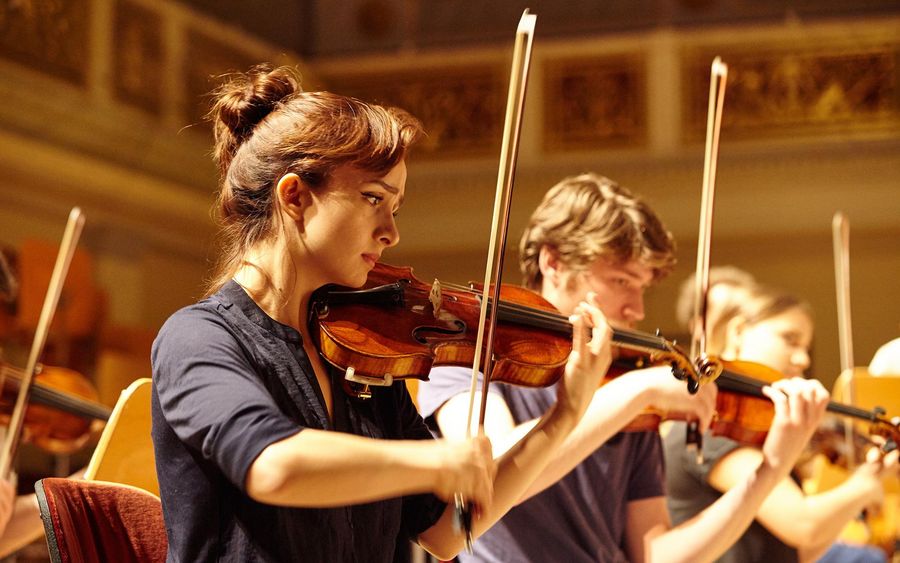 Zwei Studierende mit Geigen während einer Probe im Konzertsaal des Berliner Konzerthauses