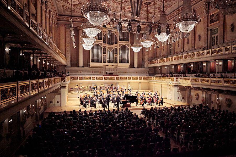 Orchester auf einer Bühne in einem Konzertsaal mit Publikum