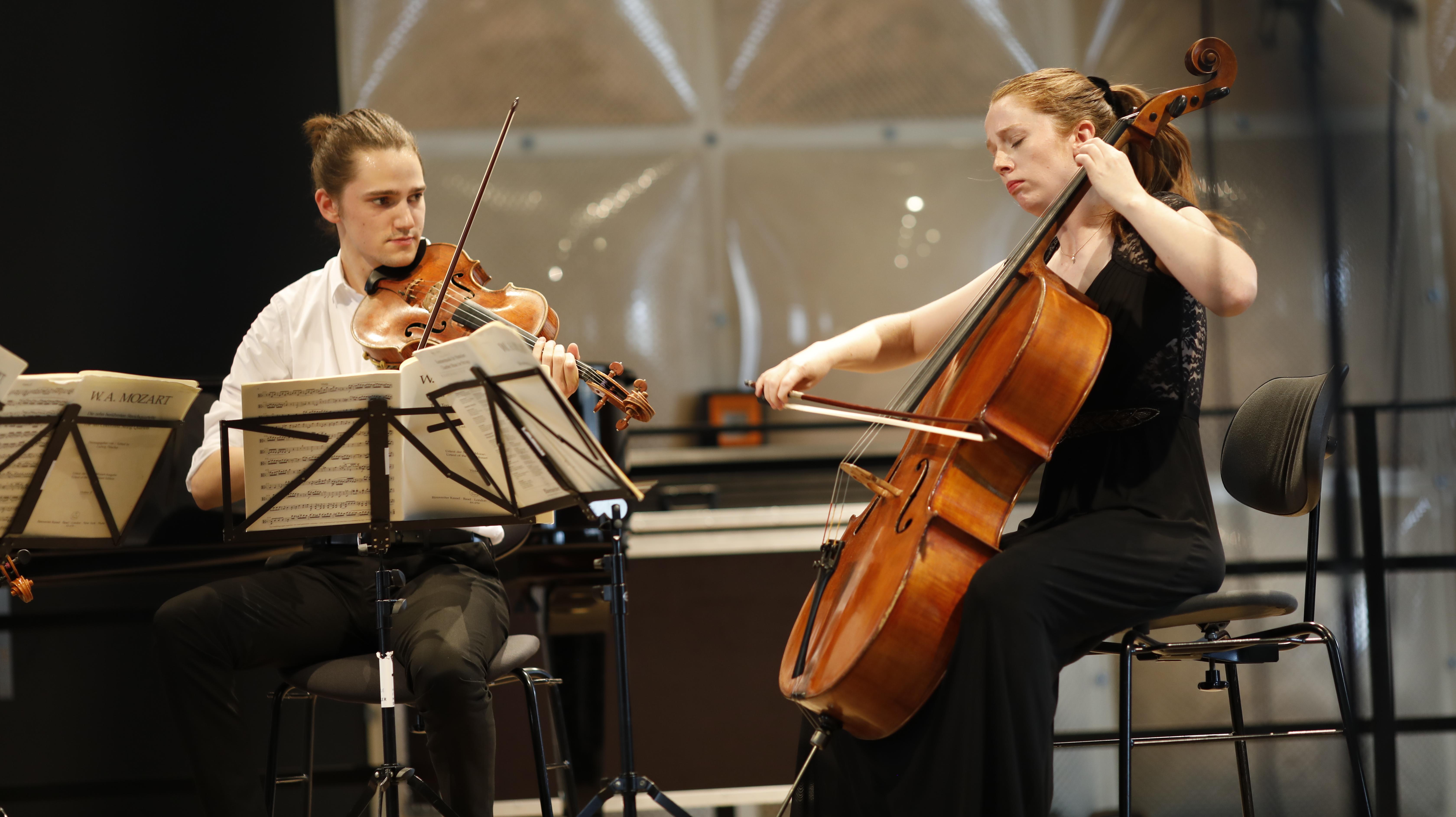 Ein Mann mit Bratsche und eine Frau mit Cello auf einer Bühne 