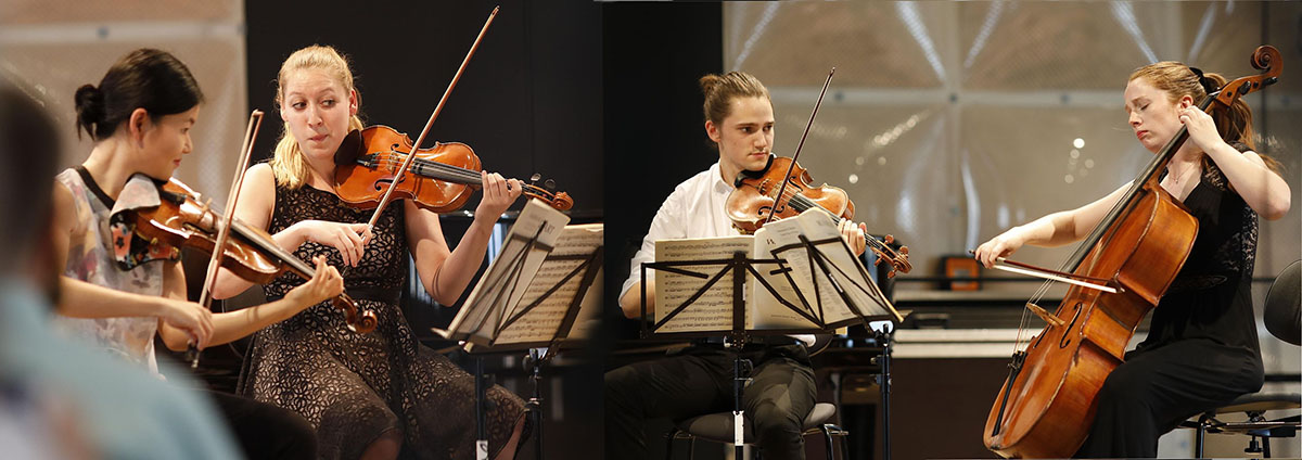 Vier Musizierende mit Streichinstrumenten und Notenständern bei einem Konzert