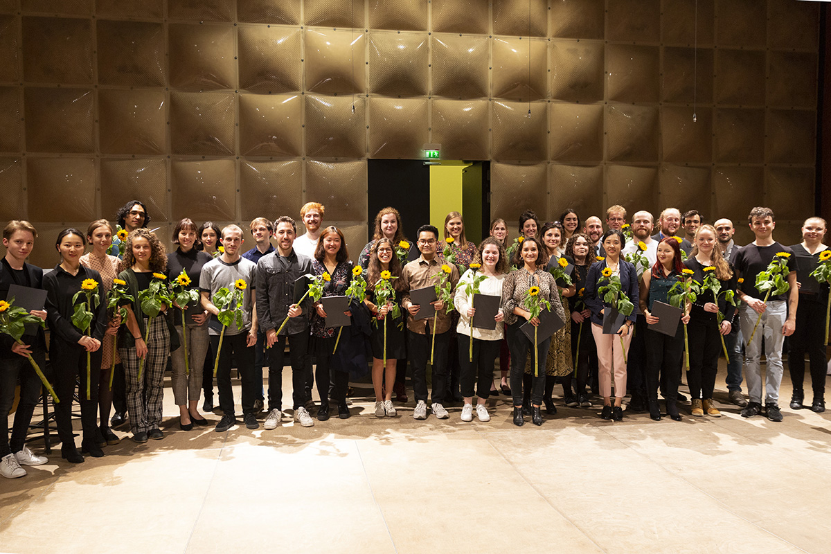 Stipendiaten und Stipendiatinnen mit Sonnenblumen und Urkunden auf einer Bühne