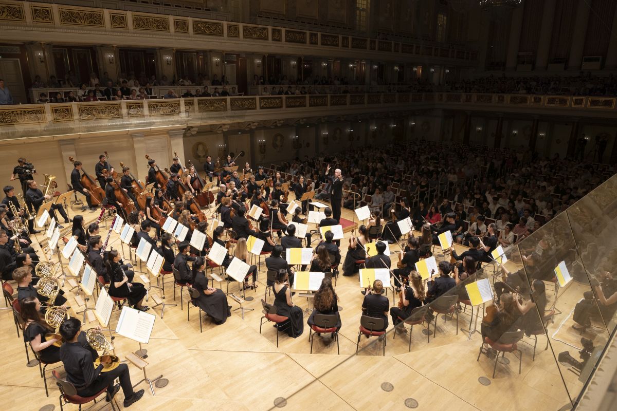 Ansicht auf das Orchester und Dirigent von hinter der Bühne