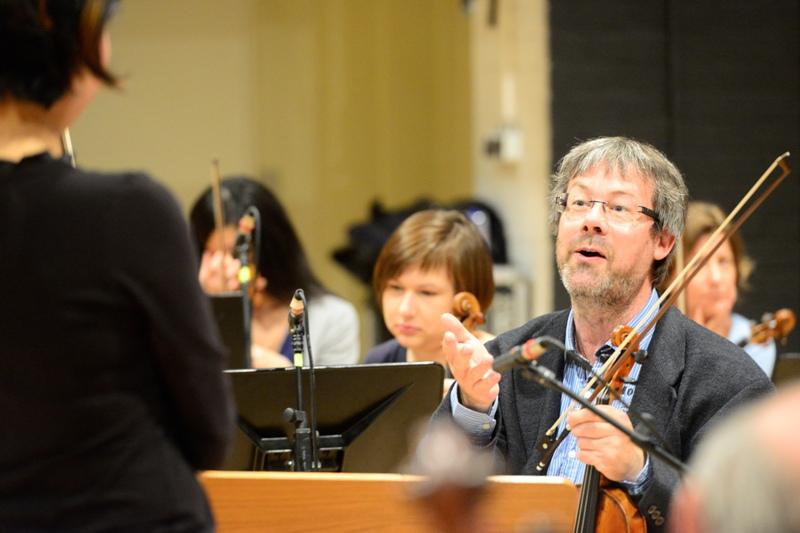 Ein Geiger spricht während einer Orchesterprobe